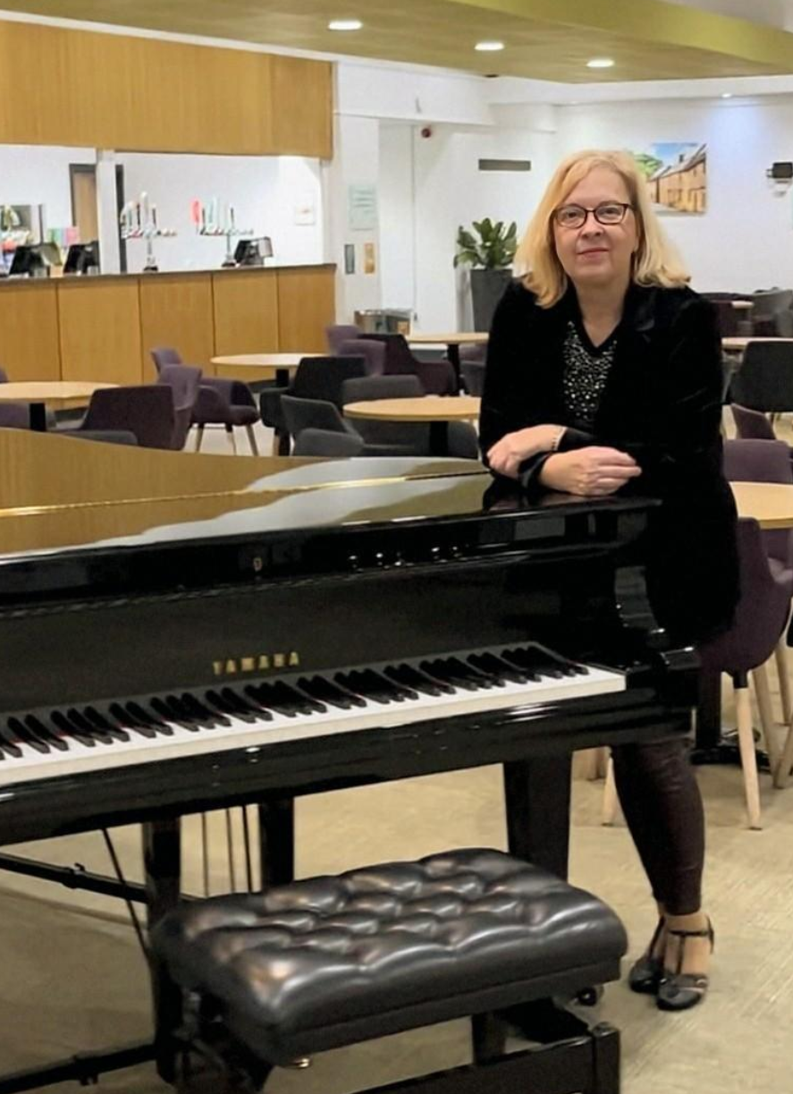 Caroline standing next to grand piano at Westlands Bar