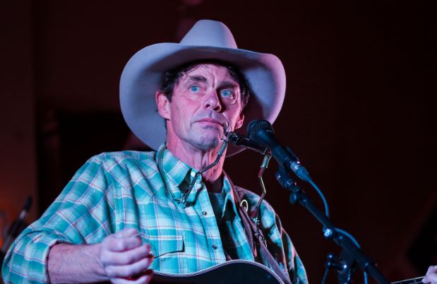 Rich Hall with hat and guitar
